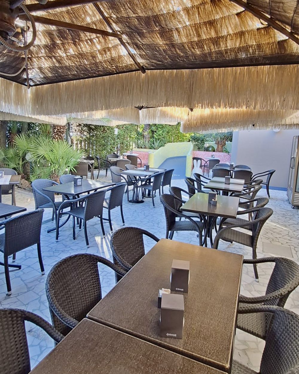 Il giardino della Gelateria 490 con i tavoli sotto gli ombrelloni di paglia