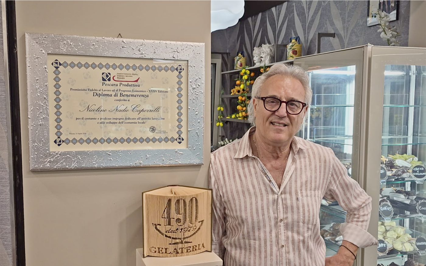 Nadio Caporrelli nella sua gelateria, accanto al diploma di benemerenza e al libro intagliato con il logo 490