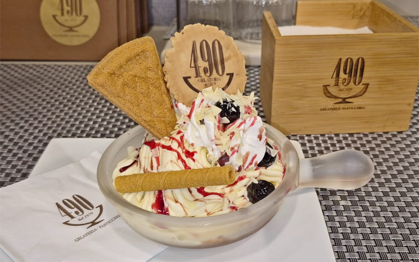 La spaghettata di gelato del 490 servita nella coppa, con panna, sciroppo di fragola, cioccolato bianco e amarene